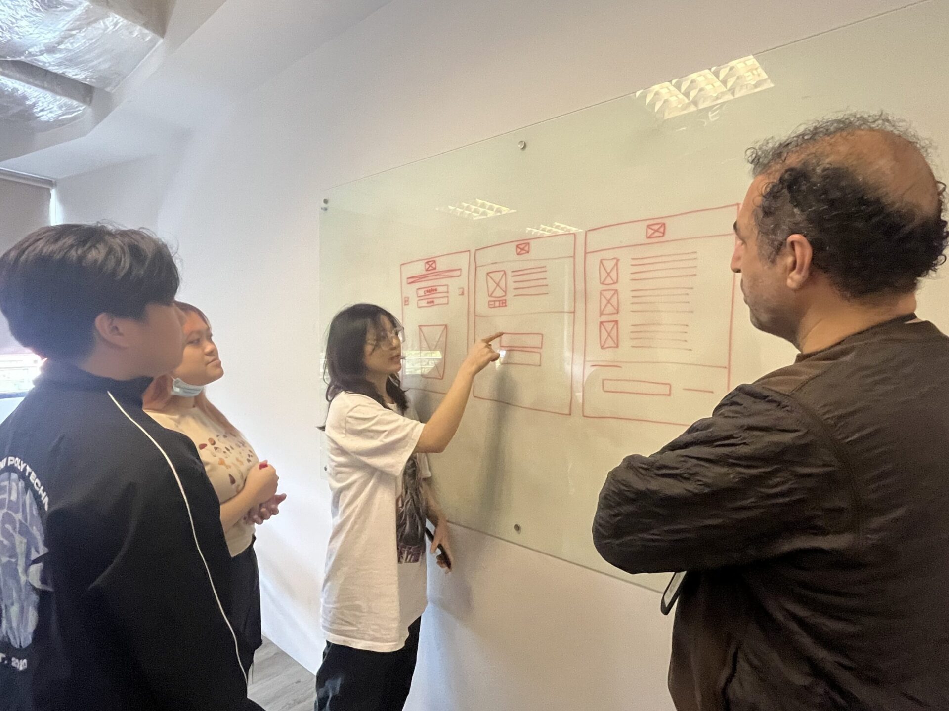 The team is going through a few low-fidelity wireframes on the whiteboard
